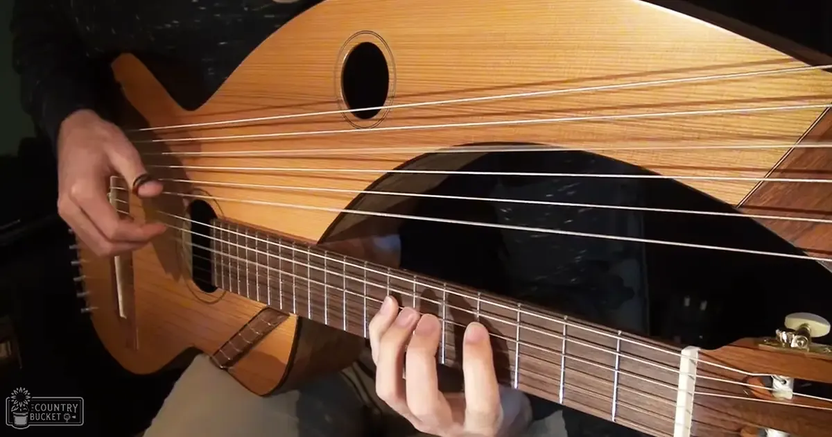 A man playing an acoustic lute indoors with dark walls and focused lighting.