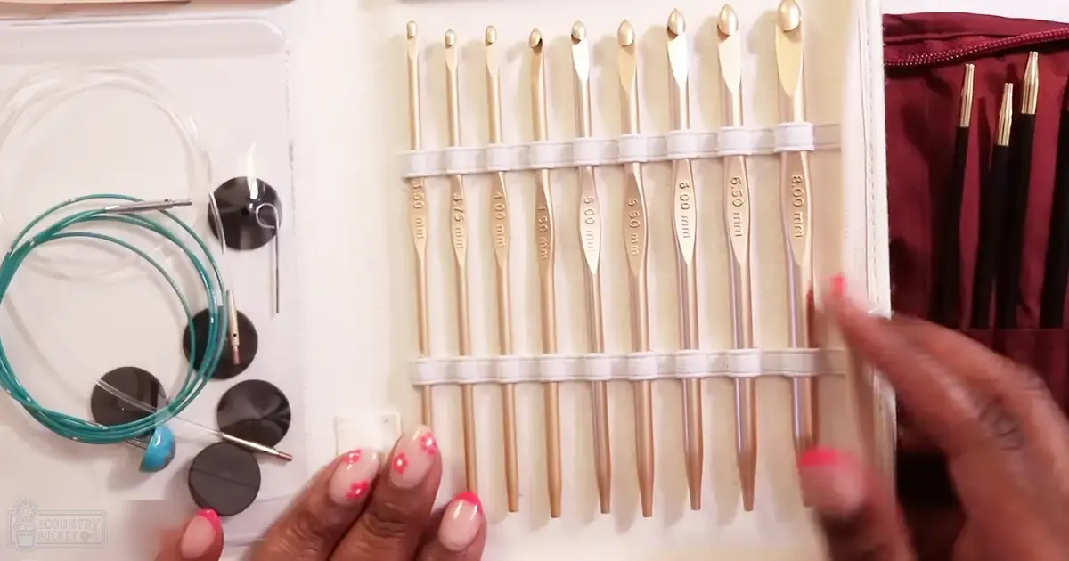 A collection of neatly arranged crochet hooks in white cases, surrounded by crafting tools like beads and weights, indoors with no discernible season or time.