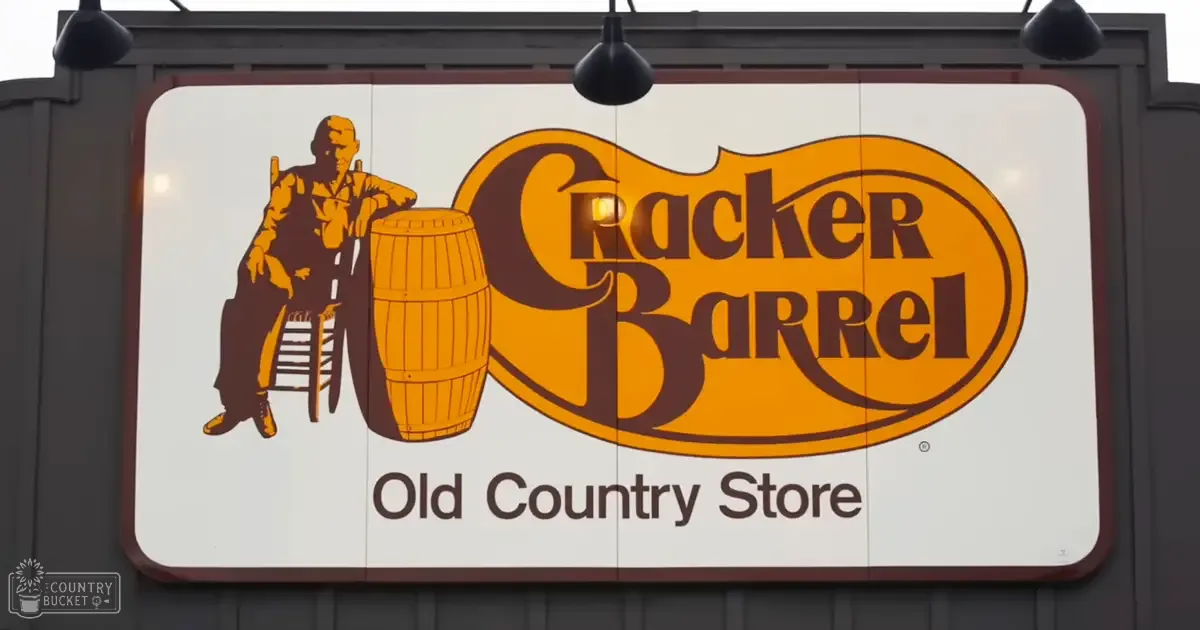 Cracker Barrel Old Country Store sign with man on ladder, outdoor setting, daytime lighting.