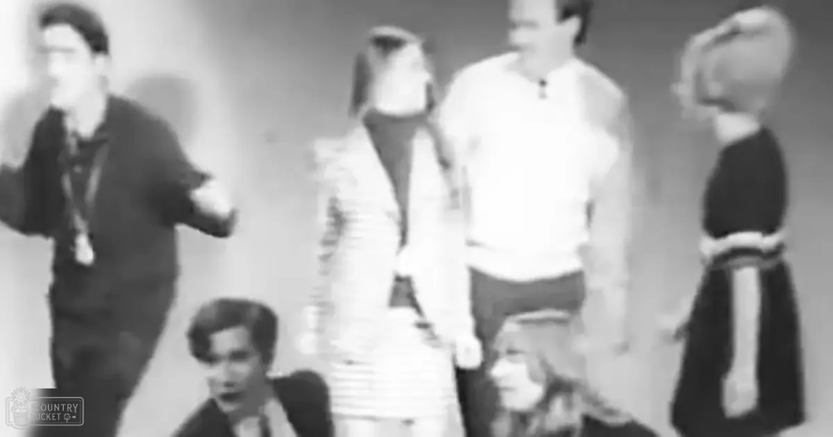 A group of young adults in formal attire indoors under artificial lighting at night, with muted tones and a black-and-white photograph aesthetic.