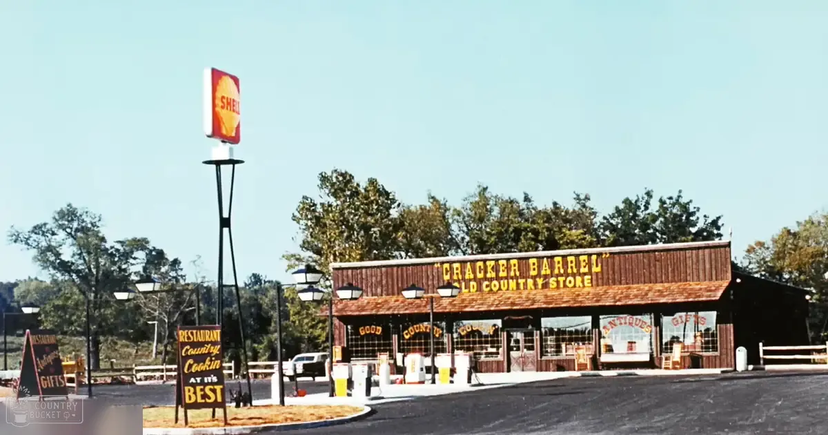 Cracker Barrel Old Country Store signage, gas station, white van, street lamps, fencing; outdoor setting with trees, daytime lighting, spring or summer greenery