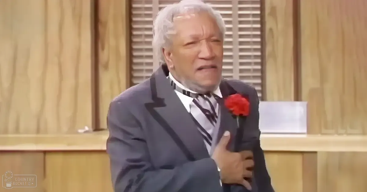 An older adult male in a formal setting, wearing a dark gray suit with a striped tie, holding a red rose. The scene is indoors with wooden paneling and shutters.
