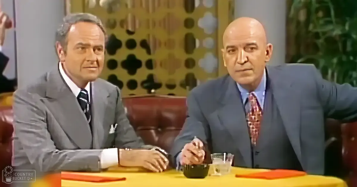 Two men in a studio setting, dressed formally with suits from mid-20th century style; leather armchairs, small black containers, glass with straw, orange napkin on table.