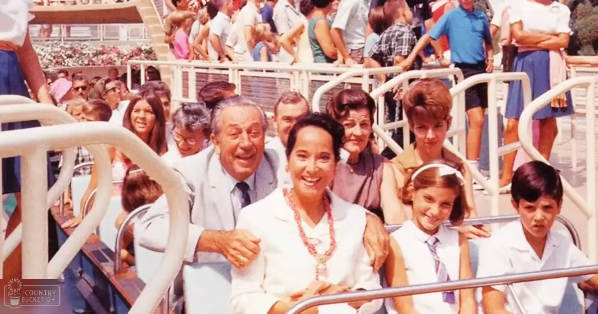 A family group enjoys an amusement park ride, with adults in formal attire and children in casual clothing. The setting is outdoors during summer.