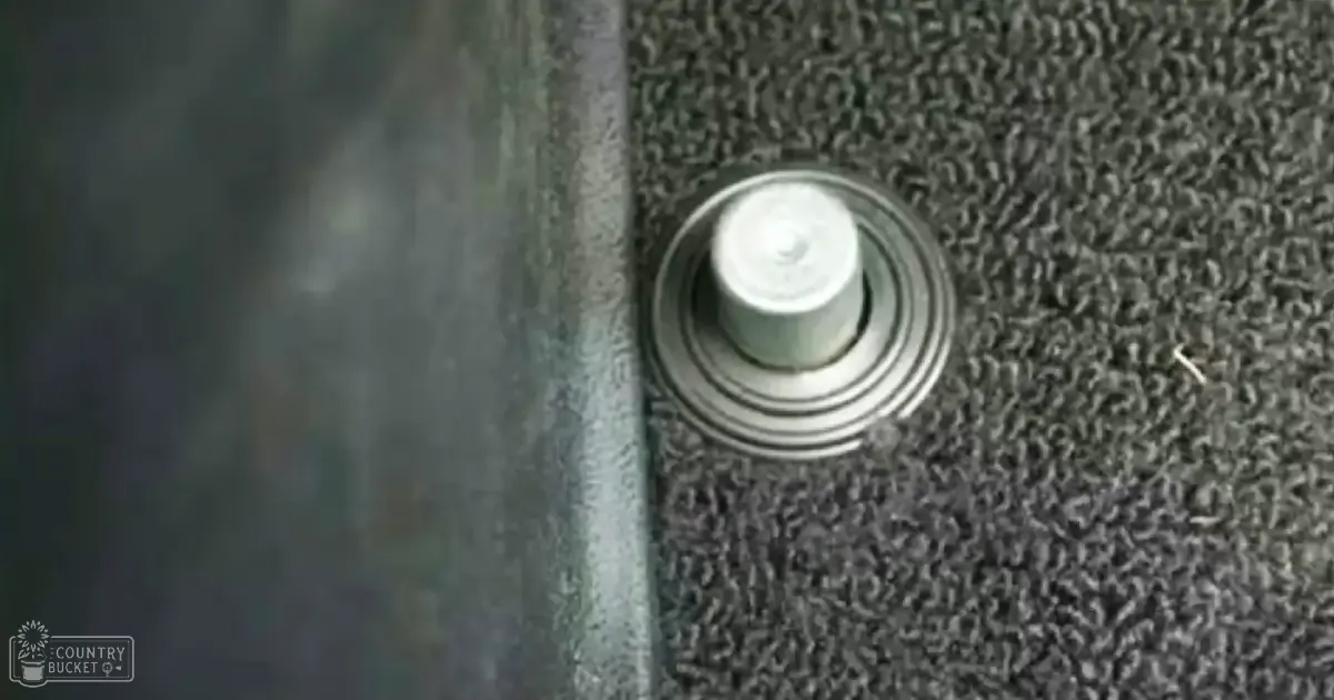 A close-up of a white button with concentric rings on a textured carpeting surface, likely indoors.