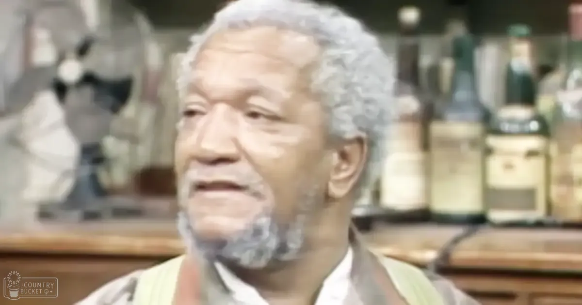 An older adult male wearing a light-colored button-up shirt in a bar setting at dusk.