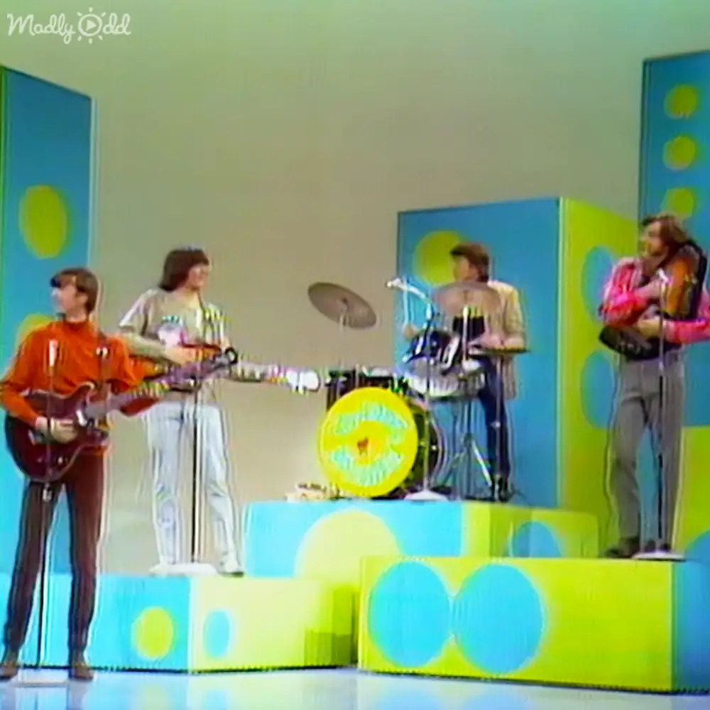 A musical performance in a studio setting with colorful backdrops and bright lighting.