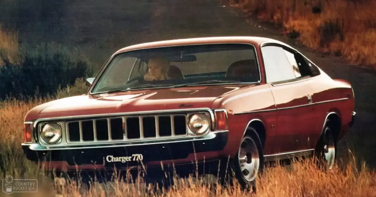 A classic 1970 Plymouth Charger 770 with chrome details parked in a rural area, bathed in warm morning or late afternoon light.