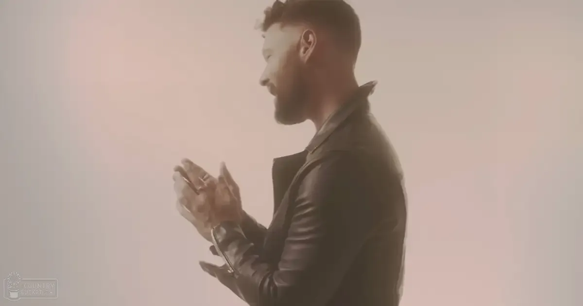 Adult male wearing a fitted, black leather jacket with zipper detail and ring, indoors with soft lighting and 'Madly Odd' text in bottom left corner.