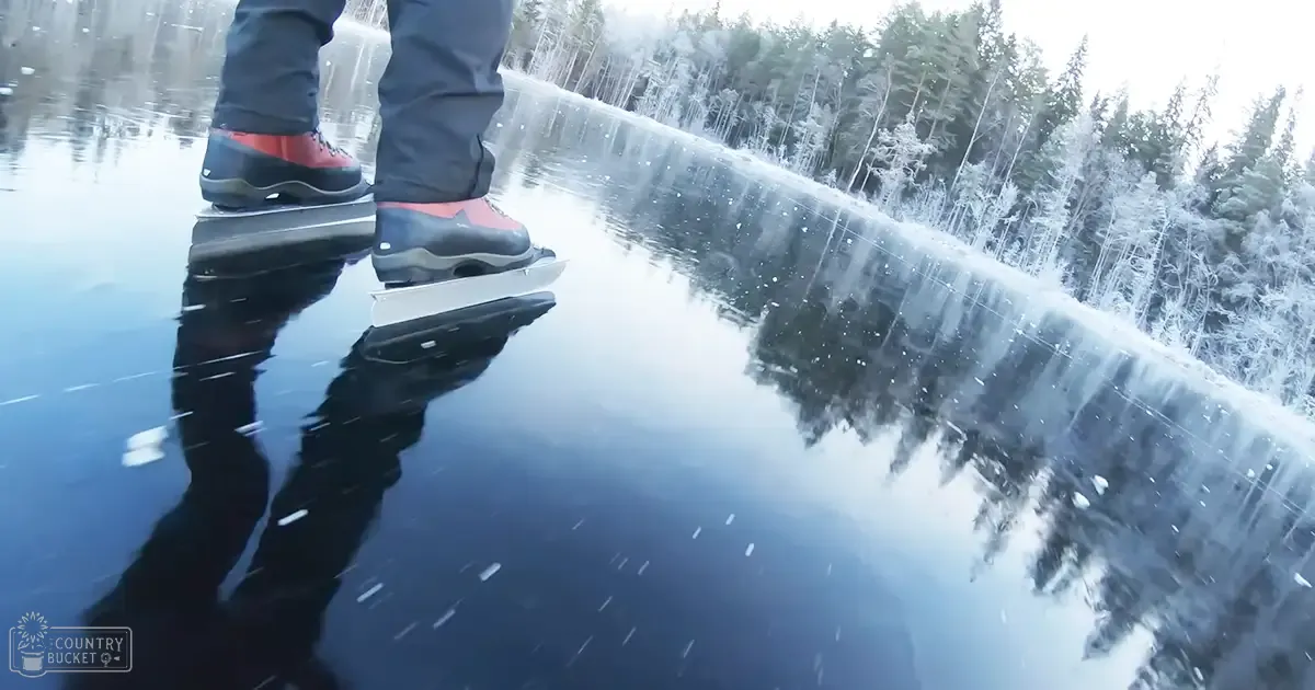 Adult male skater in dark sheen pants and red ice skates amidst a snowy forest under daylight.