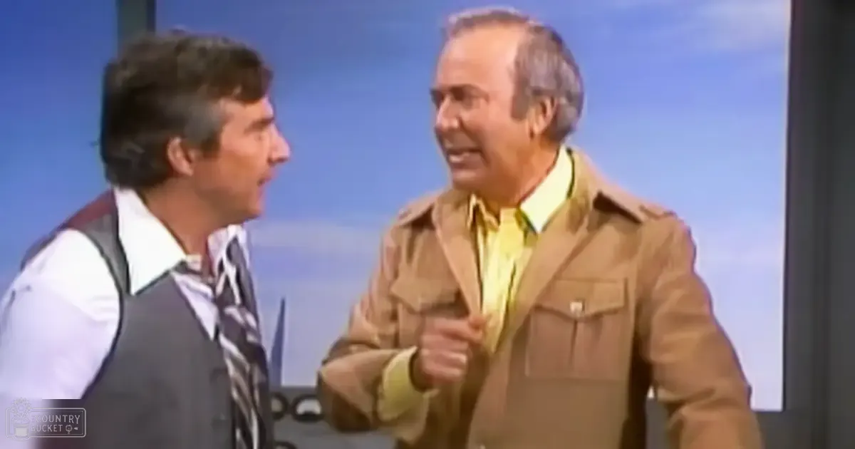 A comedic scene from a television show or sketch comedy program set indoors with a backdrop of blue skies. The setting includes part of an aircraft's tail fin, suggesting they might be at an airport.