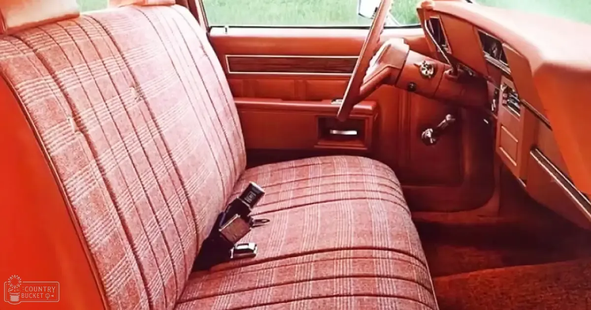 The interior of an old-fashioned vintage car with plaid upholstery, wood paneling, and a classic steering wheel design.