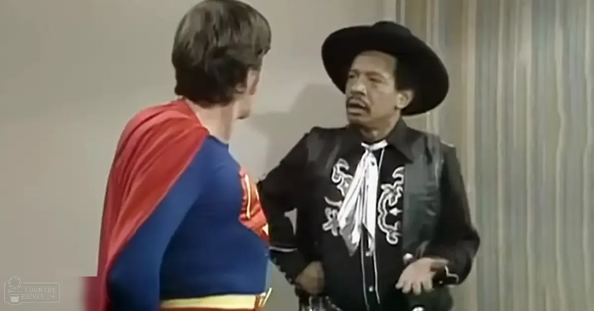 A young adult in a blue and red superhero costume stands next to an adult male wearing a black leather jacket with white embroidery, both set against a plain backdrop typical of indoor film sets.