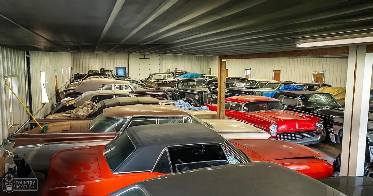 Multiple vintage cars parked in an indoor garage setting with natural lighting and visible furniture, suggesting preparation for weather conditions.