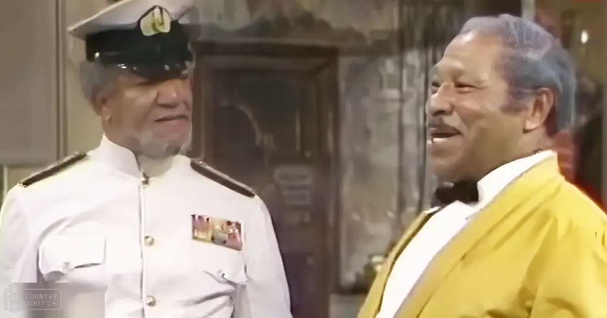 An adult male singer in a historical naval uniform with an older adult male in a formal mid-20th-century attire, set indoors within a building like an office or home during daytime conditions.