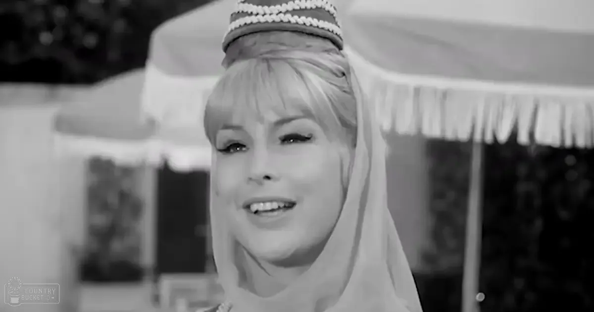 A middle-aged woman wearing a traditional veil-like headpiece adorned with pearls in an outdoor setting during the daytime.