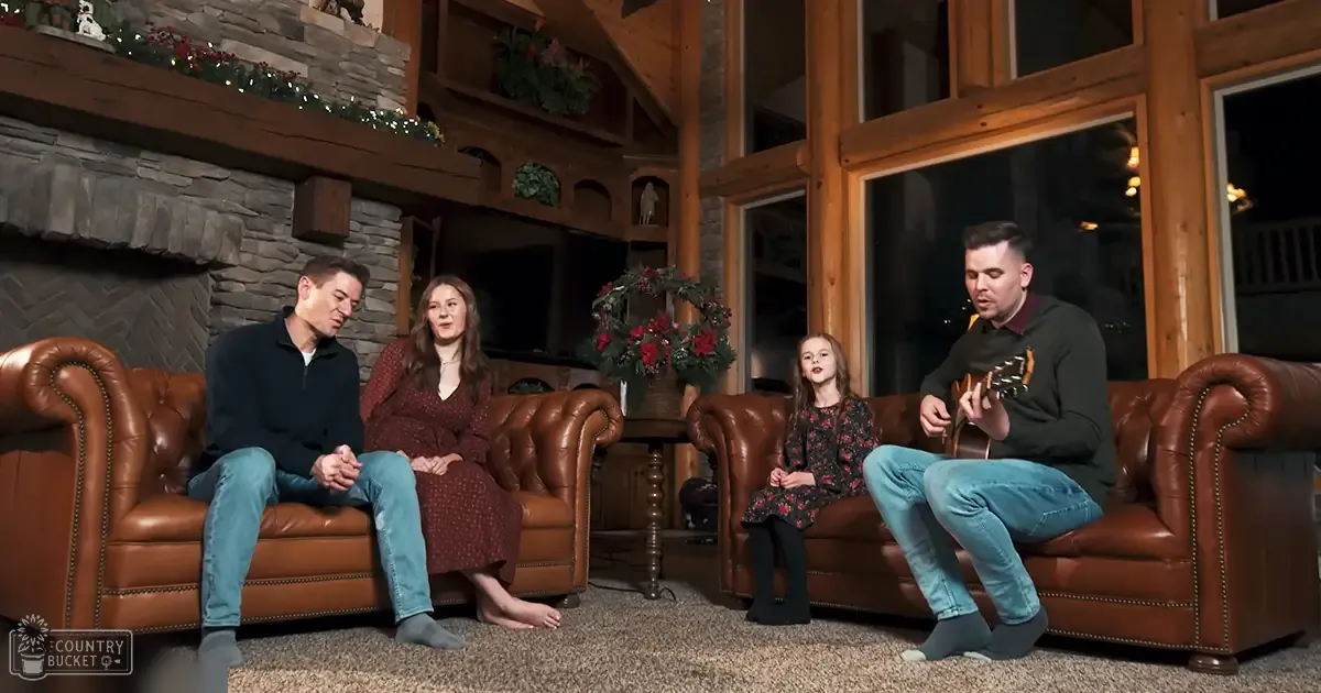 A cozy indoor living room scene during the holiday season with two brown leather sofas, a stone fireplace decorated for Christmas, and family members in casual attire.