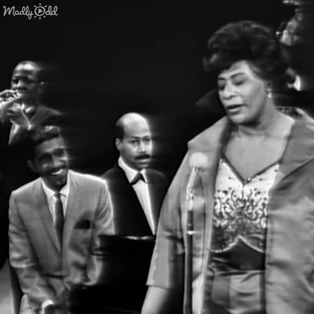 A woman singing in front of a microphone at what appears to be an indoor performance venue.