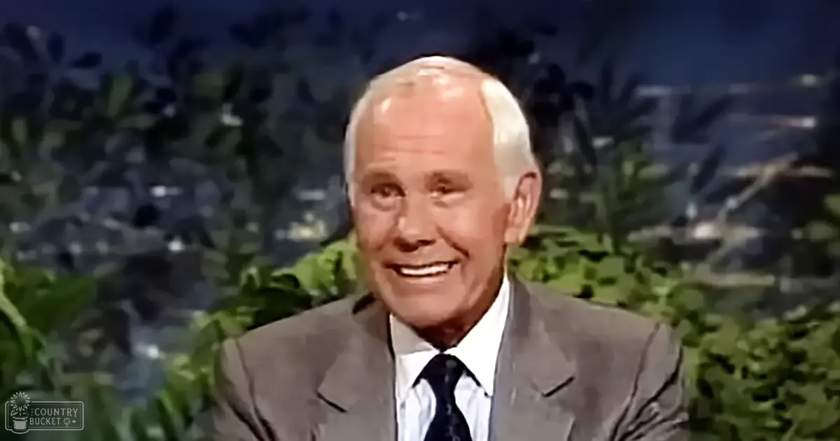 An older adult male in a studio setting with tropical foliage and cityscape hints, wearing a dark gray suit jacket from the mid-20th century or early 1960s.