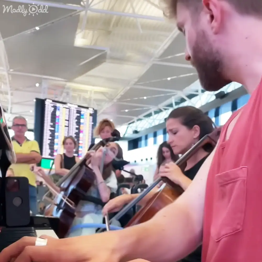 Musical performance by young adult male piano player and female cellists in an airport terminal with natural light streaming through large windows.
