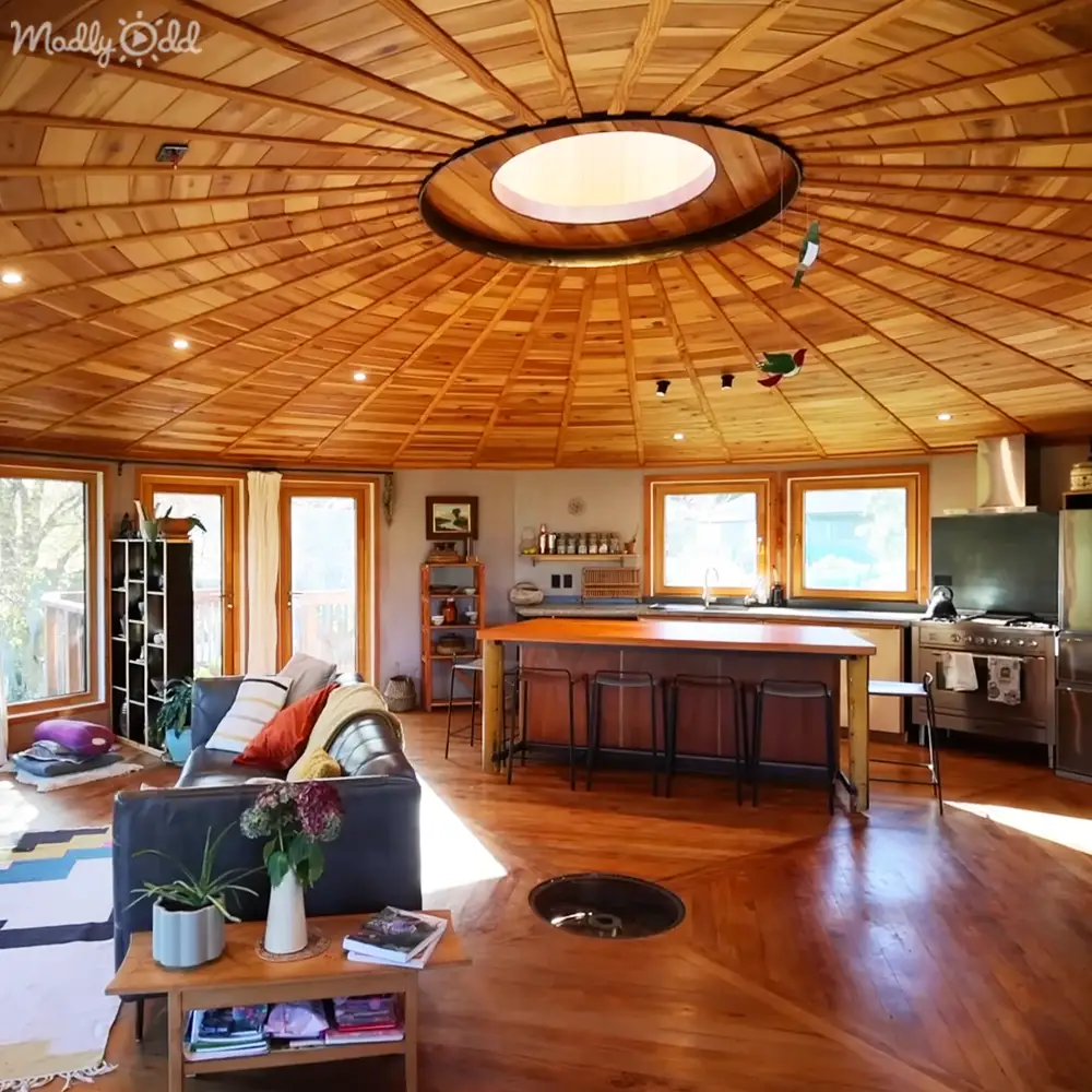 An indoor scene with a cozy, rustic living space with wooden furniture, colorful throw pillows, and natural light streaming through large windows.