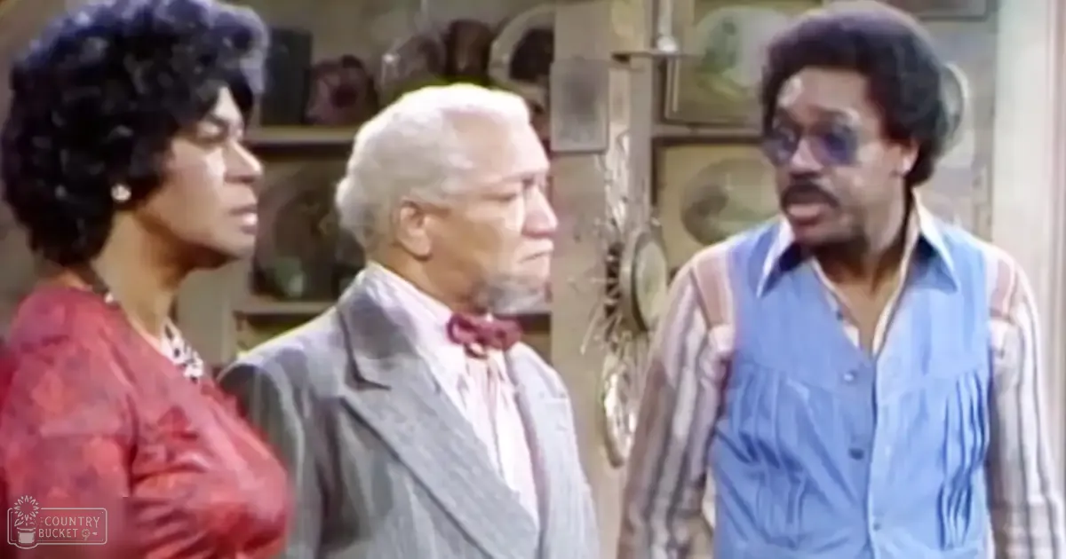 Middle-aged man in a light gray suit with an older adult female wearing a red floral top indoors, surrounded by personal decor suggesting a home environment.