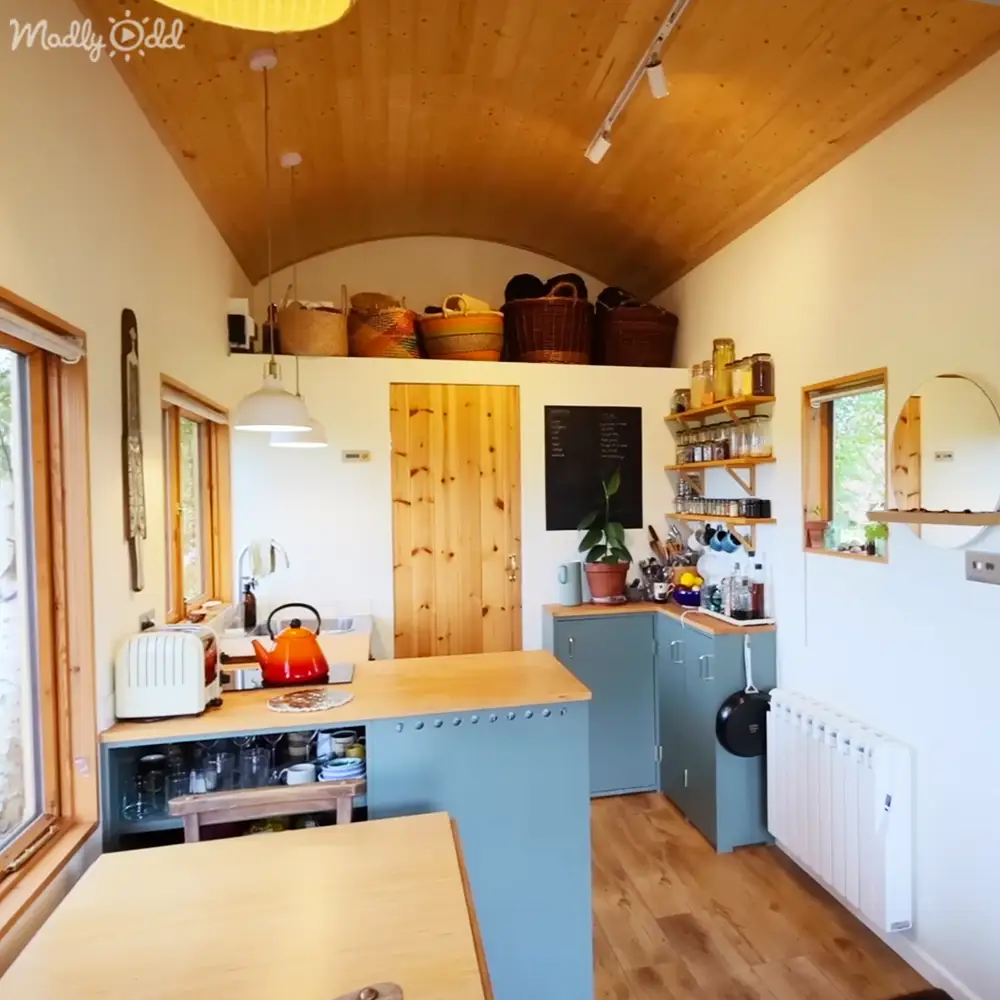 A cozy kitchen interior with blue cabinets, wooden countertop, and natural light streaming through a window.