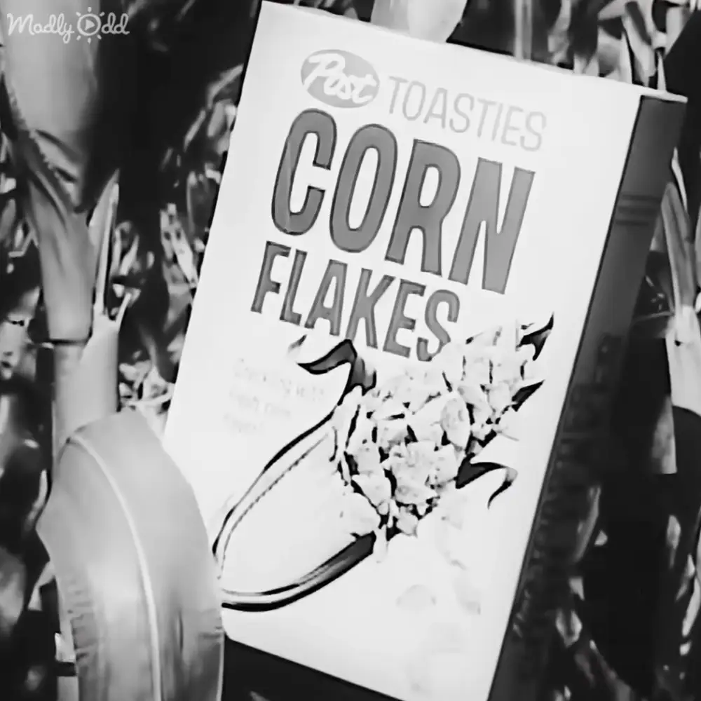 A cereal box for Post Toasties Corn Flakes displayed outdoors with other stalls or displays visible in the background.
