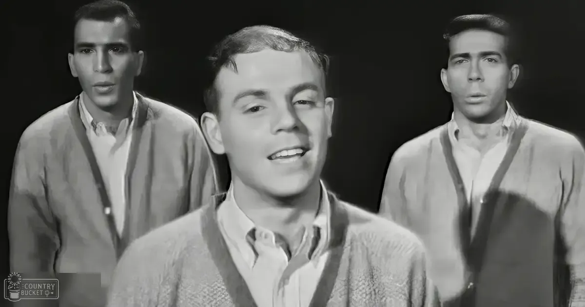 A young adult male central figure, flanked by two other individuals in an indoor setting with dark and plain background.