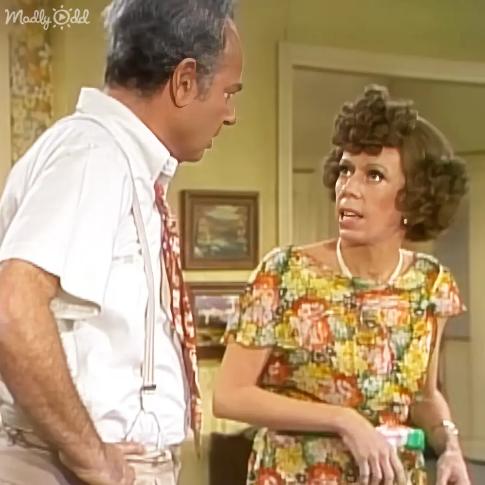 A mid-20th-century kitchen scene with a man in a white shirt and suspenders, and a woman in a colorful floral dress, with natural lighting and home decor elements.