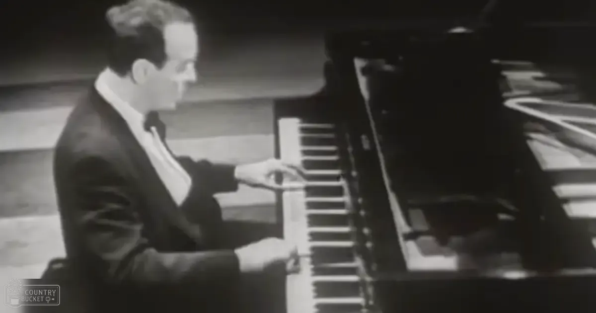 Adult male playing piano indoors with dim lighting.