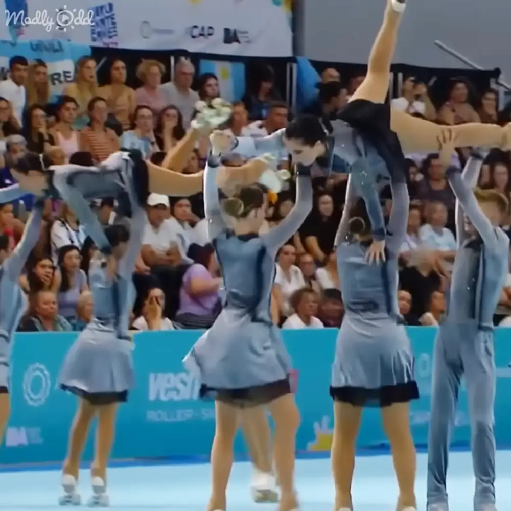 A group of cheerleaders in an indoor arena or gymnasium performing their routine.