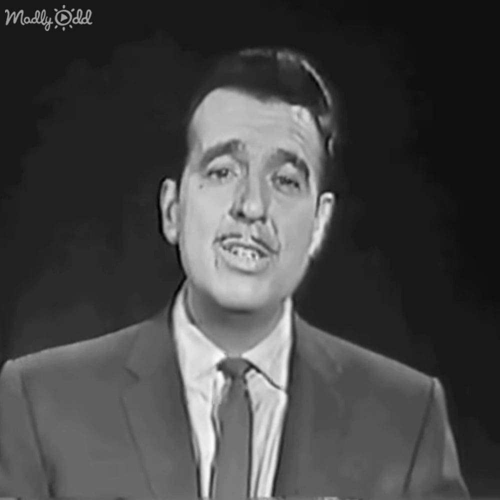 Adult male in a mid-20th century suit jacket with a dark tie against a simple backdrop typical for television broadcasts or studio recordings.