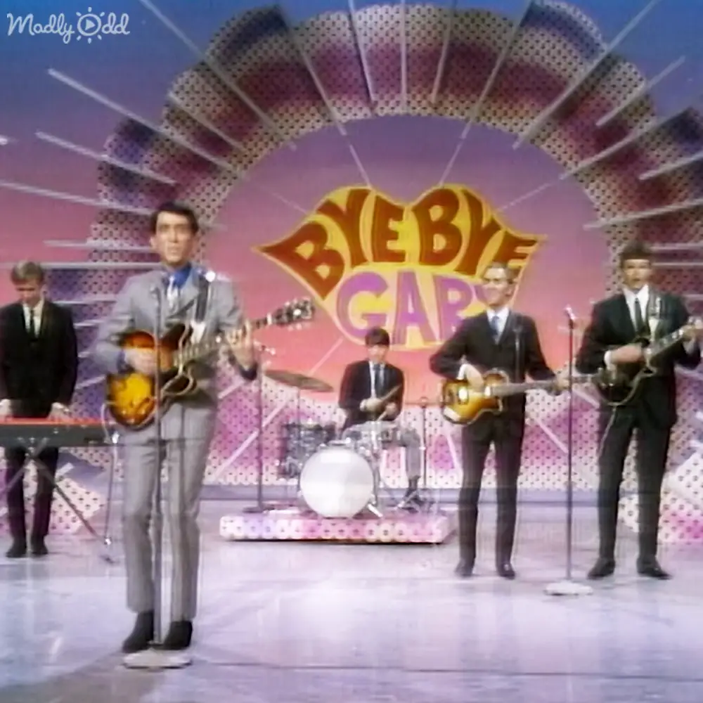 Musical performance on a retro-designed stage with musicians playing instruments and a circular backdrop with 'BYEBYE GAB'.