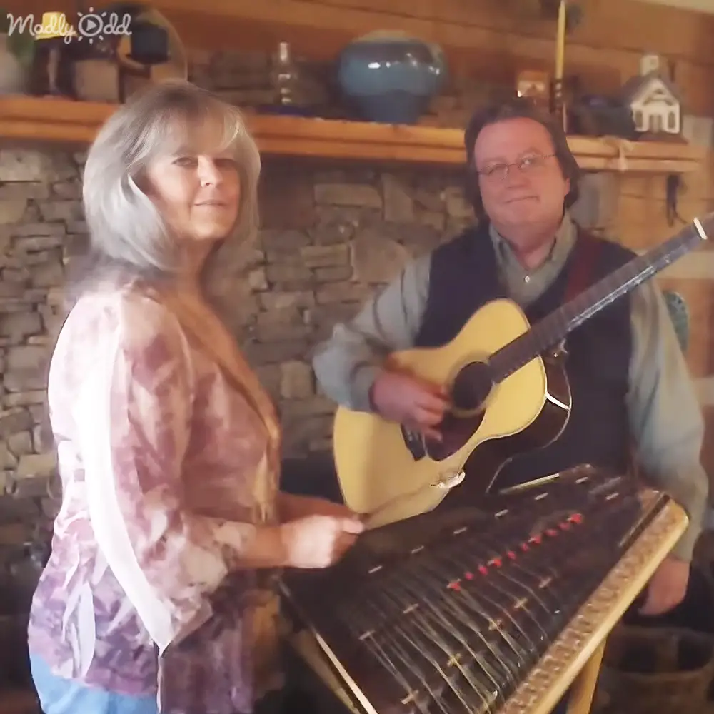 A musical performance in a cozy indoor setting with stone walls, wooden beams, and shelving units filled with various items.