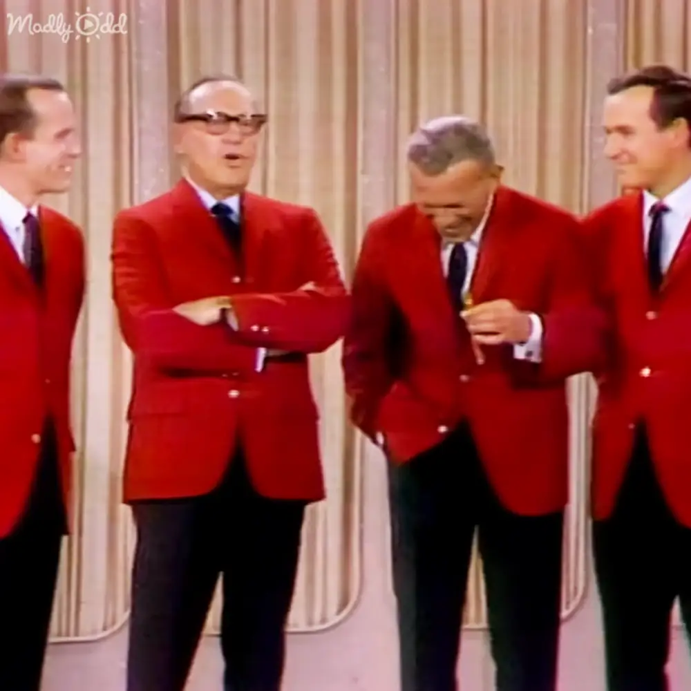 Group performance scene with four adult males wearing red mid-20th century blazers on a stage set against curtains, typical of entertainment venues from the past.