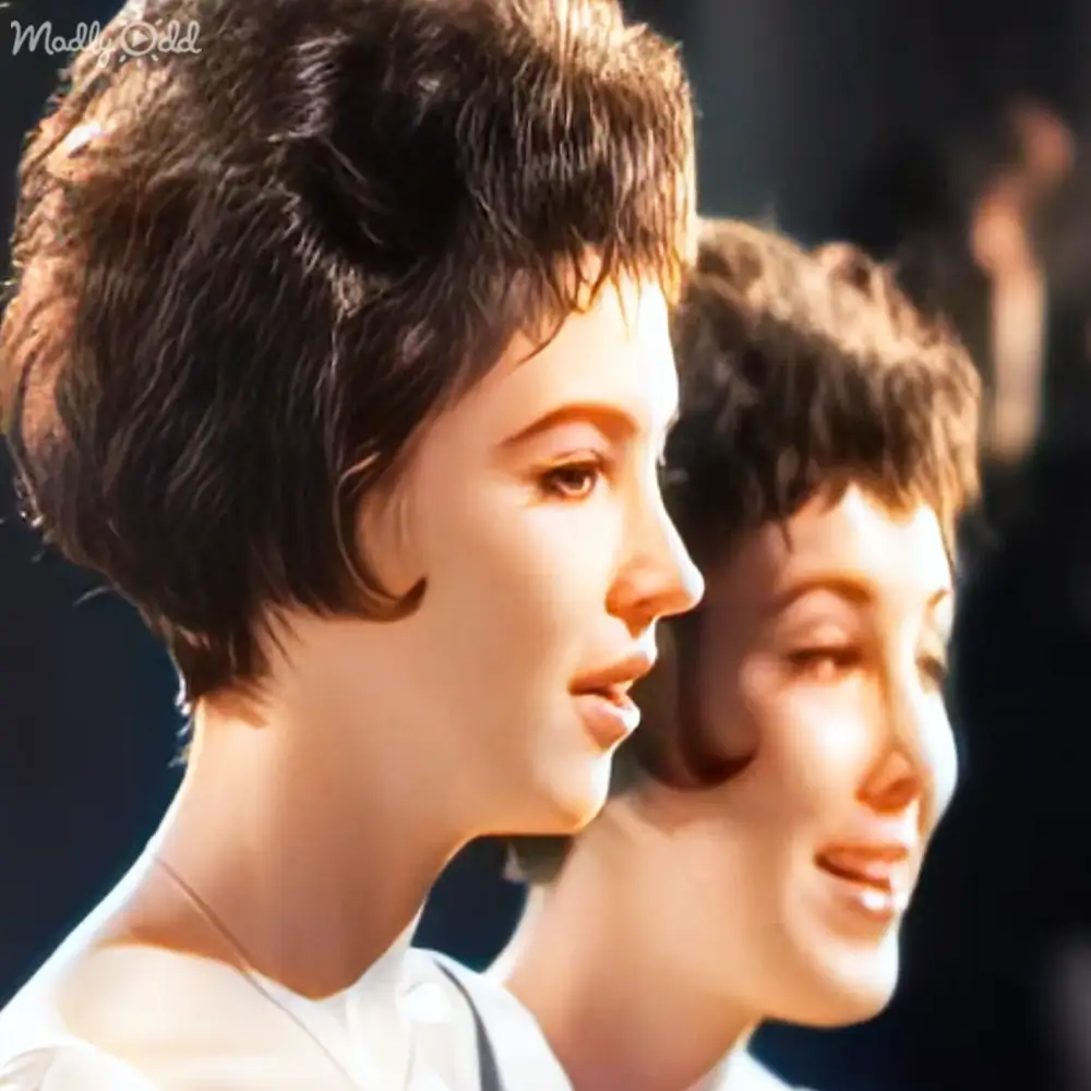 Two young adult females outdoors in natural light, wearing simple garments with white and dark blue/black color schemes.