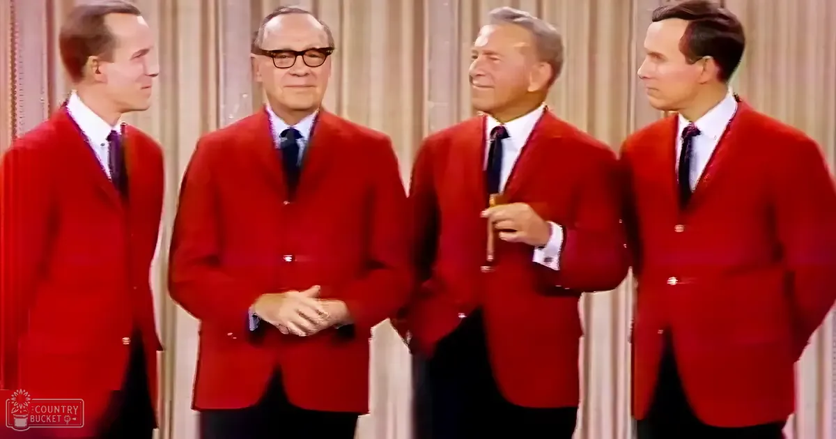 Four men wearing red jackets and white shirts, performing indoors with beige curtains as the backdrop.