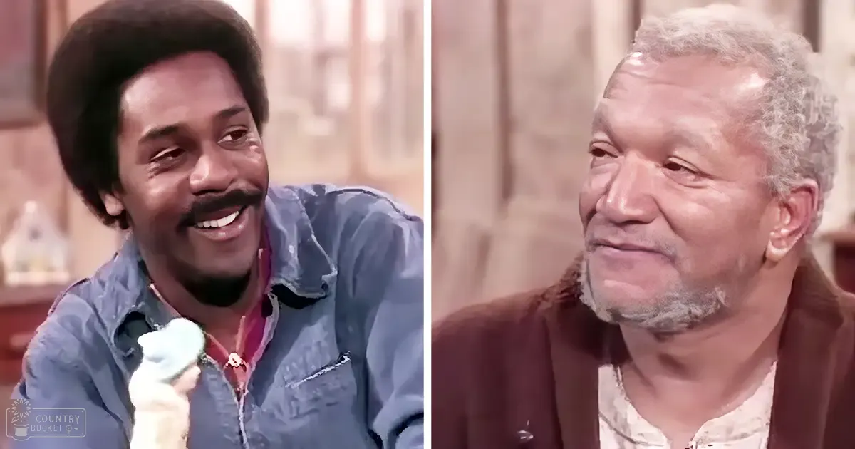Adult male singer wearing a blue denim shirt with pink collar and holding a small figurine, older adult male wearing brown cardigan over white patterned shirt with earrings, kitchen or dining area set from an older television show.