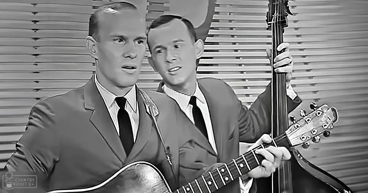 Two adult male singers in a recording studio setting with dark suits and light shirts, performing music.