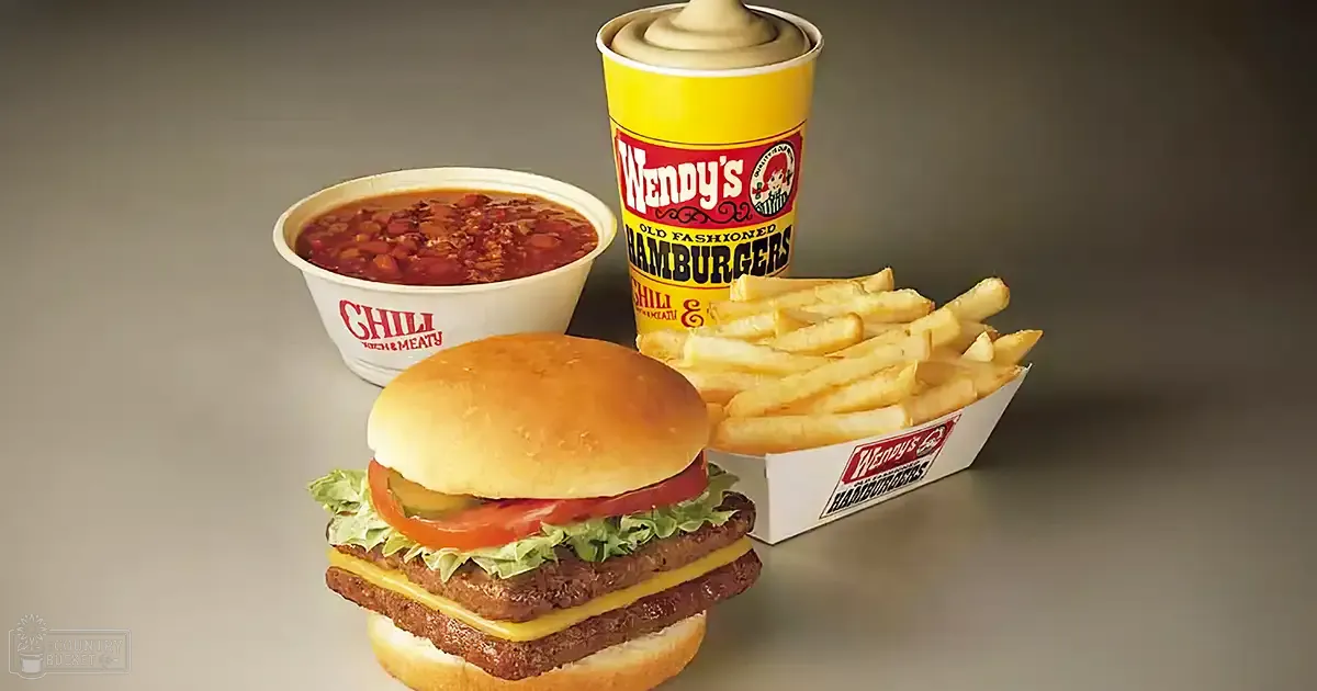 Wendy's meal with a hamburger, chili bowl, and Old Fashioned Hamburgers cup in a restaurant setting with neutral background.