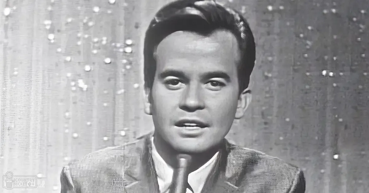 Young adult male in a formal blazer and dress shirt against an indoor backdrop with textured curtain.