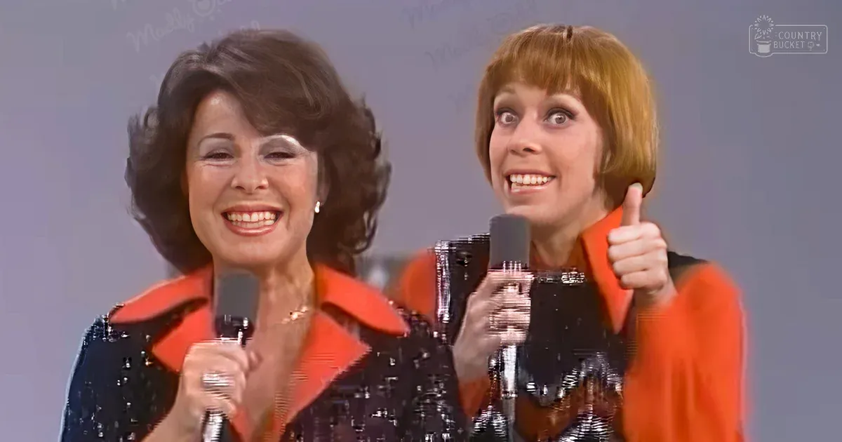 A middle-aged female in a dark sequined dress with an orange collar, alongside a young adult female wearing a bright orange sequined jacket, both from the mid-20th century, performing on stage against a light-colored backdrop with 'Madly Odd' text.