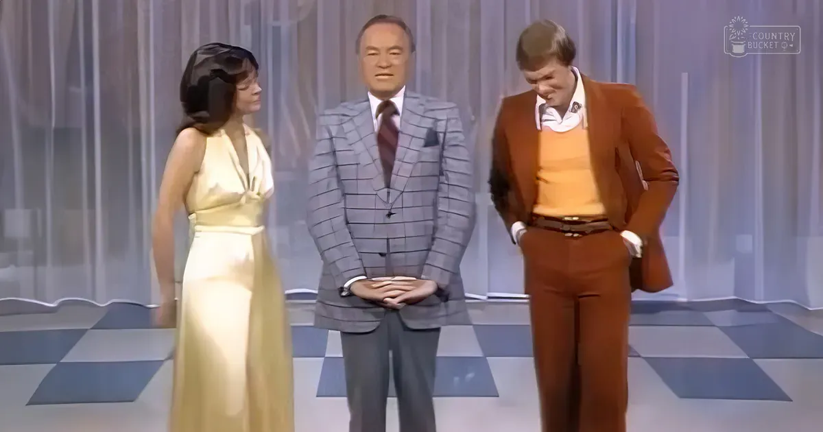 A television studio set with simple curtains and checkered flooring, likely designed for a talk show or game show in the 1970s.