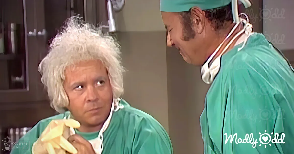A middle-aged man and an older adult male in green surgical gowns stand together in what seems like a hospital setting, with artificial lighting illuminating their interaction.