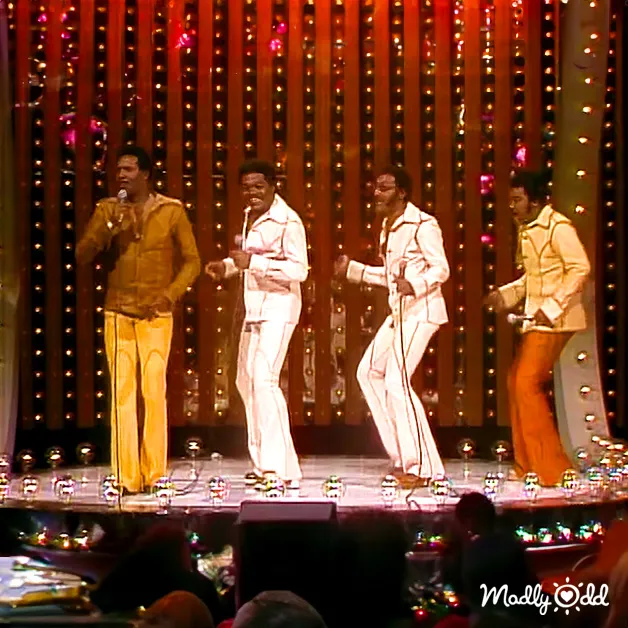 A musical performance with performers wearing suits on a stage in an indoor venue with festive lighting.
