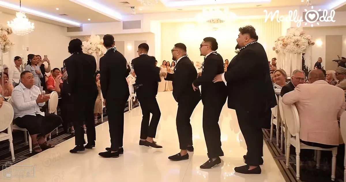 A wedding ceremony with adult male attendees in black suits, white shirts, and loafers, seated amidst classic white chairs and floral arrangements under bright chandeliers in an indoor venue.