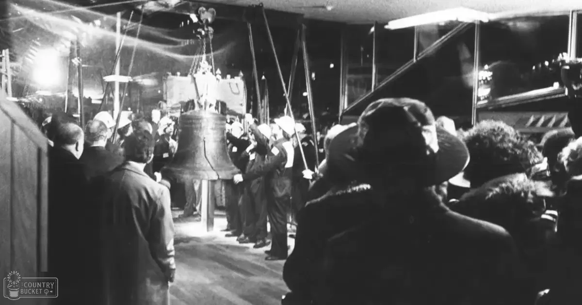 Middle-aged adults wearing fur-lined coats in an industrial workshop setting, with heavy machinery and dim artificial lighting.