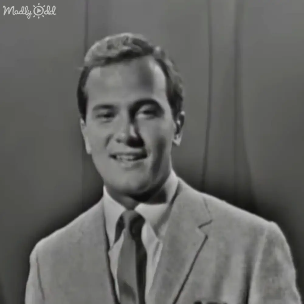 Middle-aged adult male in a tailored suit jacket, collared shirt with tie, indoors with artificial lighting.