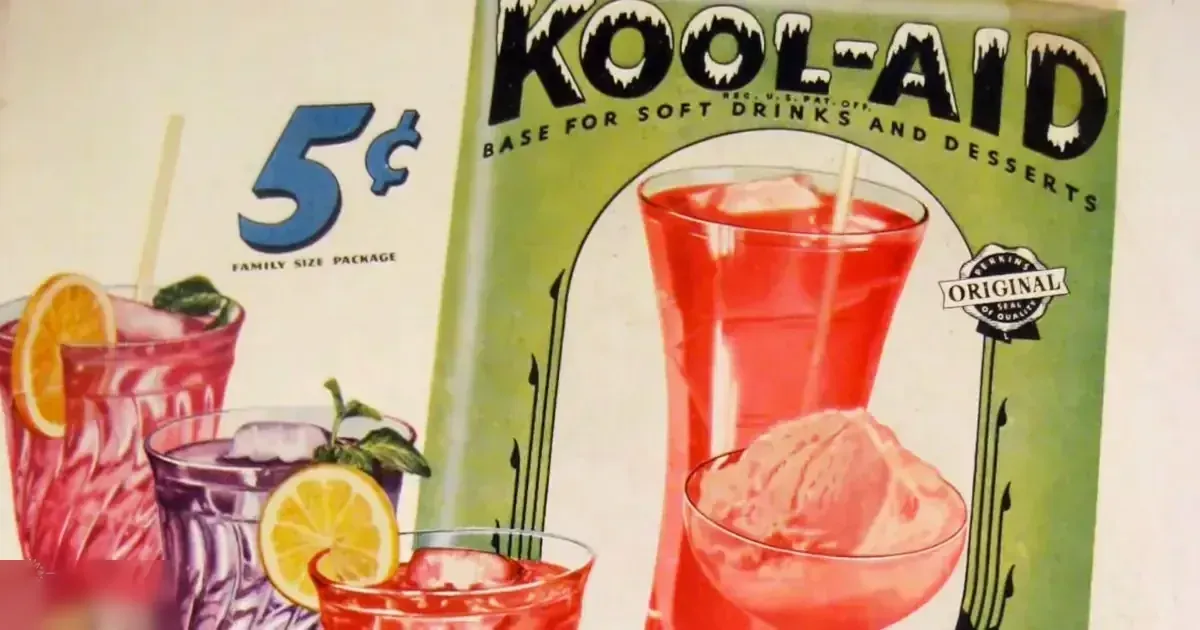 An indoor studio setting with a plain white background showcasing vintage Kool-Aid advertisements with glasses of various colored beverages, ice cubes, lemon slices, mint leaves, a pitcher of Kool-Aid mix, and an ice cream scoop.